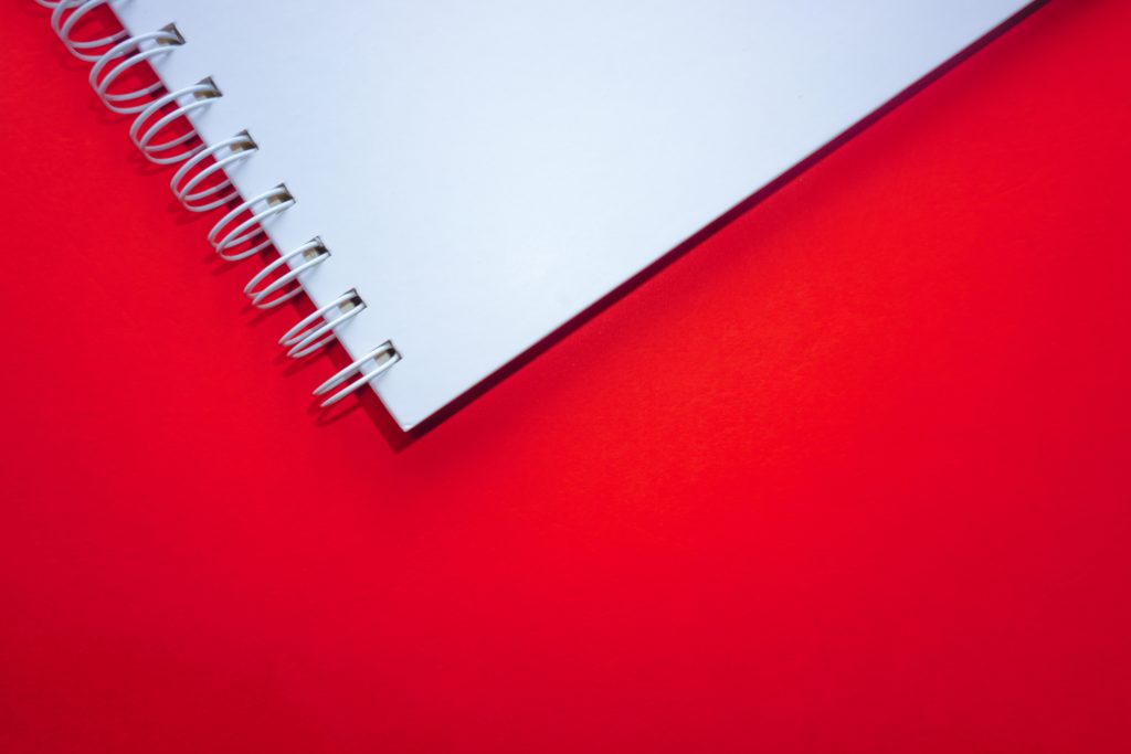 An open blank notebook against a bright red background