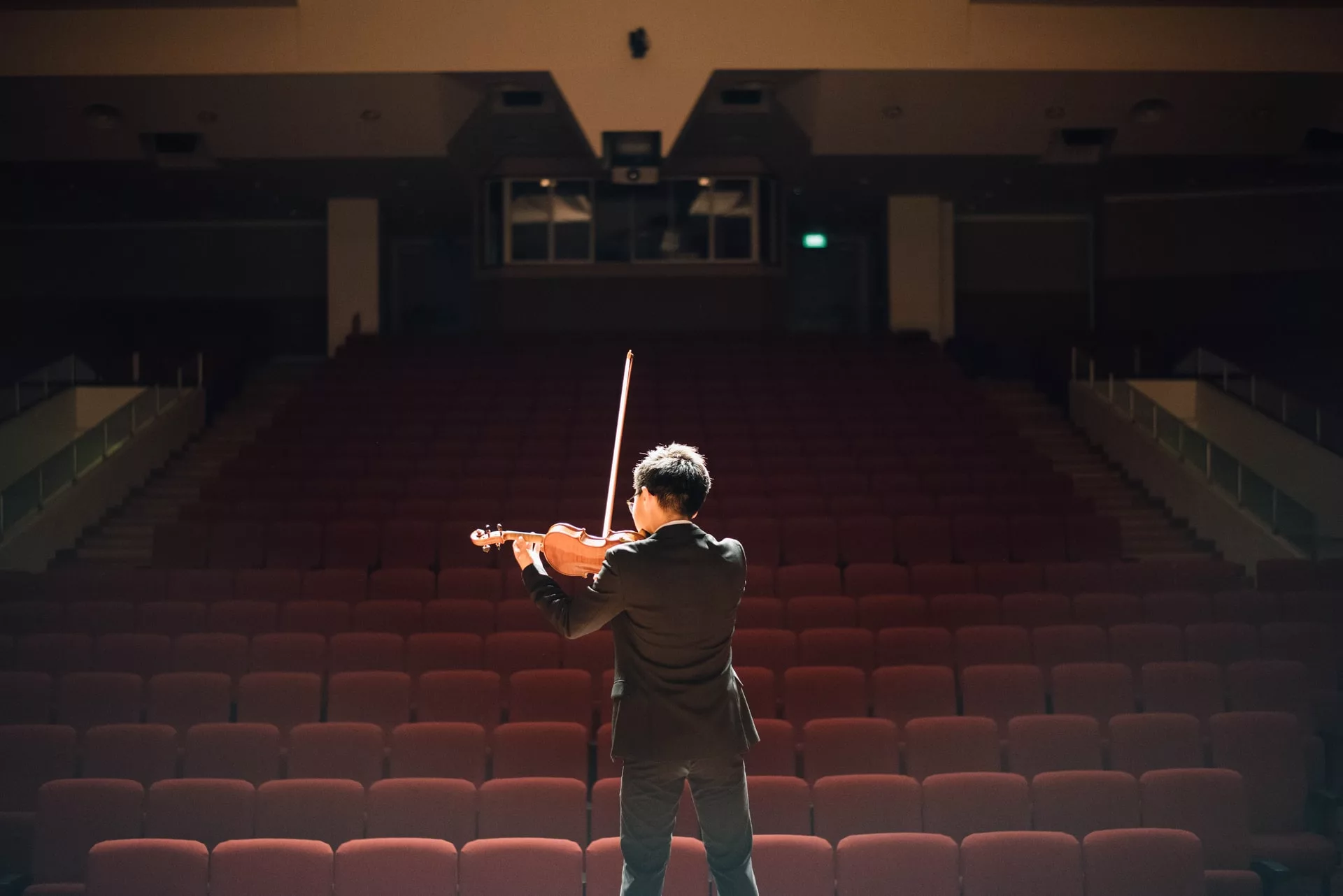 Violinist playing in front of an empty concert hall