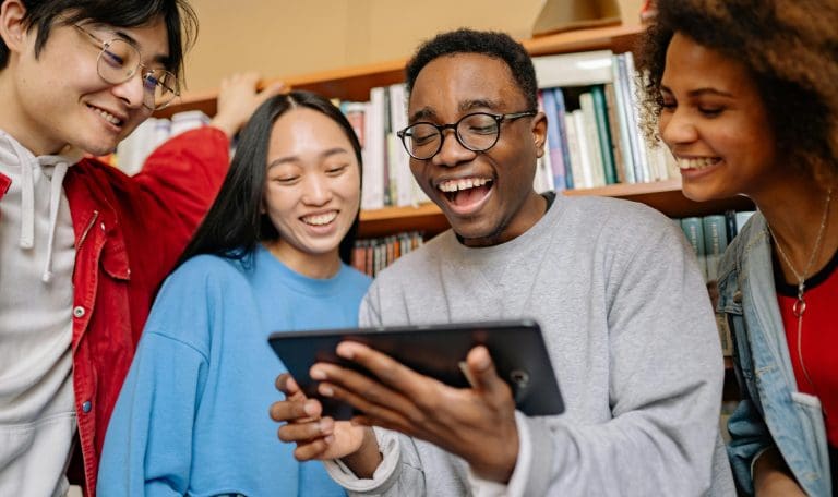 college students looking at an ipad together in a library