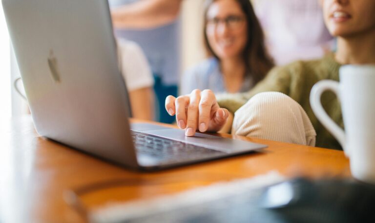 Two people looking at a laptop together drinking coffee