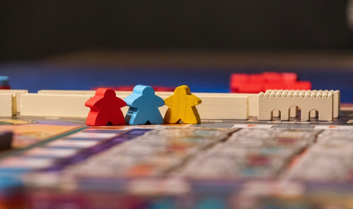 A red, blue, and yellow game board piece sitting on top of a board game