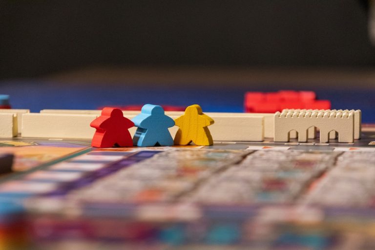 A red, blue, and yellow game board piece sitting on top of a board game