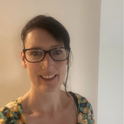 smiling woman wearing black rimmed glasses and a floral shirt