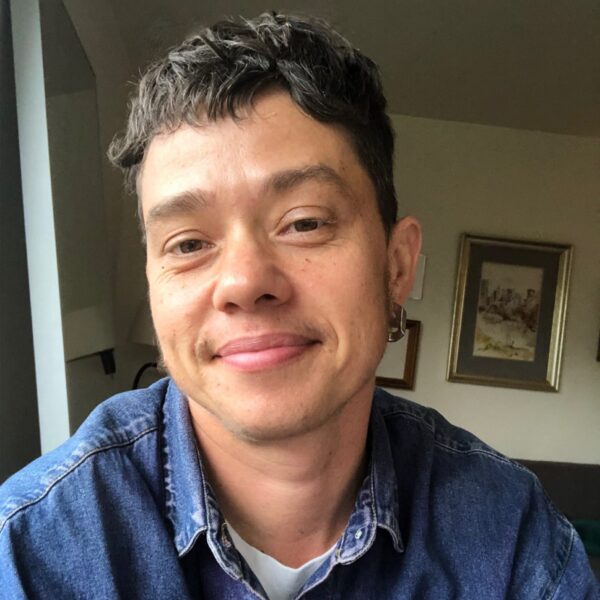 Person smiling wearing a denim button up shirt