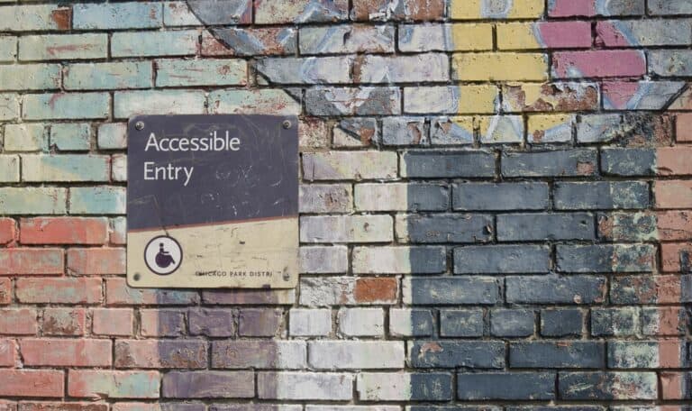 graffittied wall with a sign that says "accessible entry"