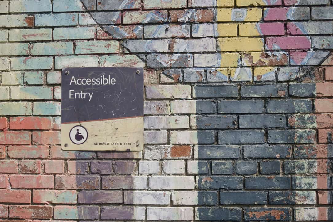 graffittied wall with a sign that says "accessible entry"