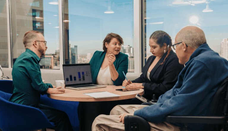 a small groupd of colleagues working together at a table in front of a window
